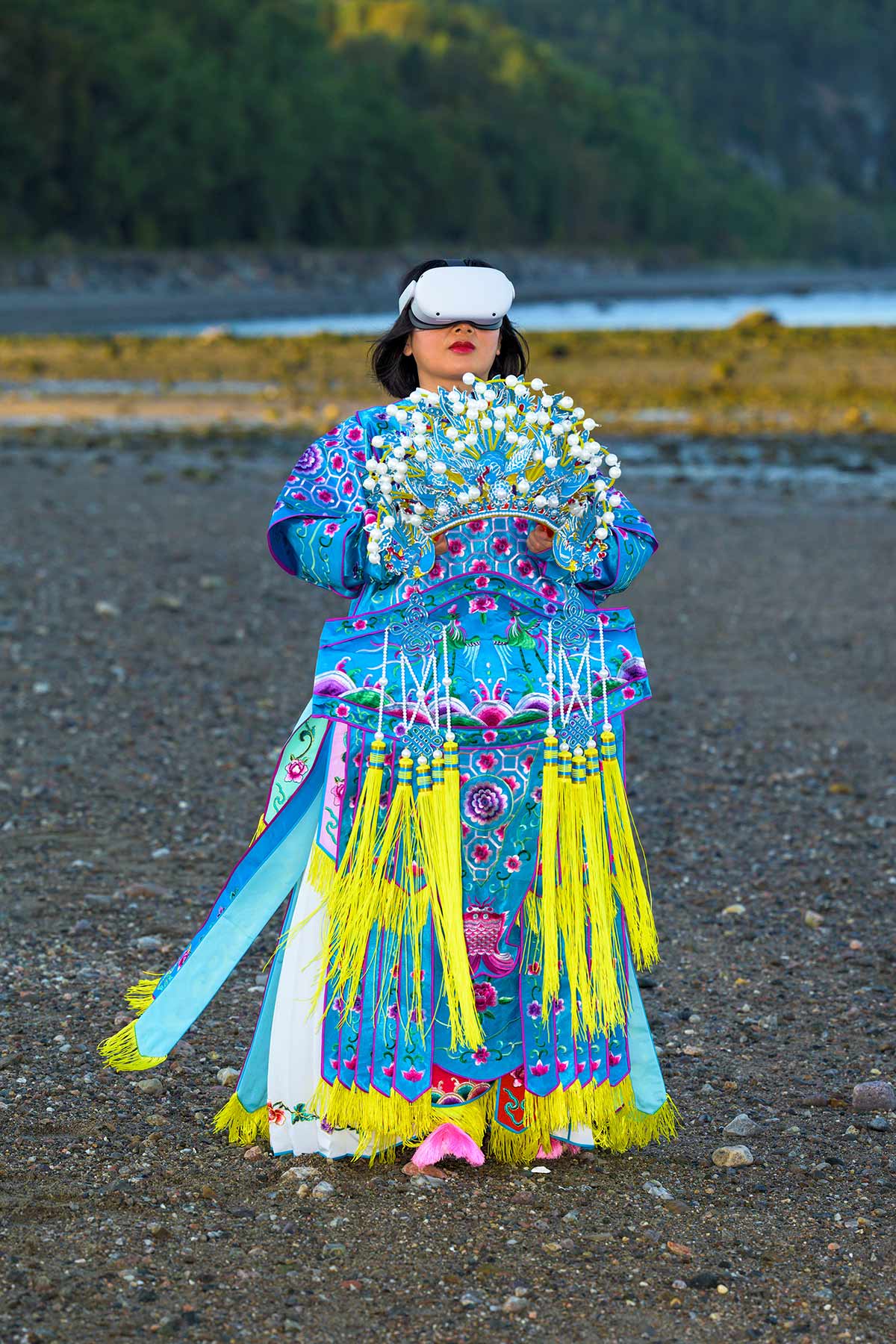 Chun Hua Catherine Dong wears Oculus VR headset and a blue Chinese opera costume with a phoenix crown on her hands beside The St. Lawrence River.