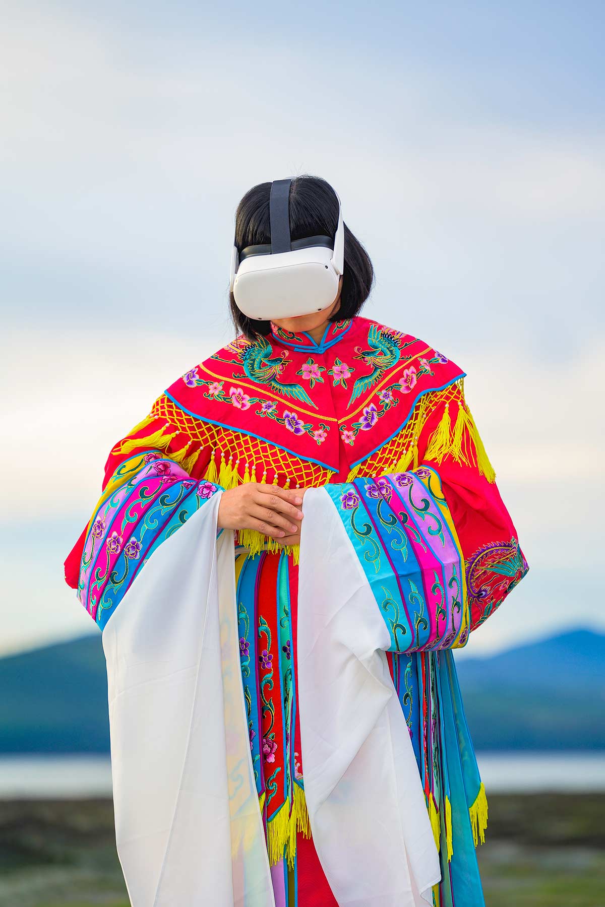 Chun Hua Catherine Dong wears Oculus VR headset and a red Chinese opera costume beside the St. Lawrence River.