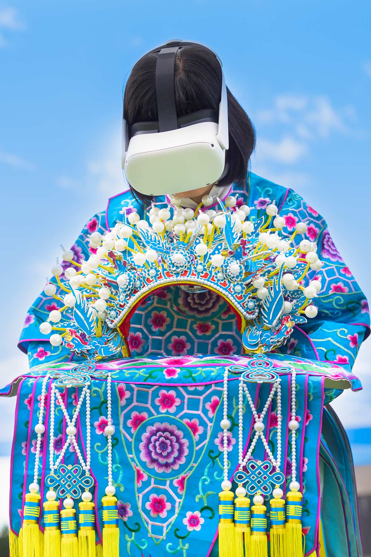 Chun Hua Catherine Dong wears Oculus VR headset and a blue Chinese opera costume with a phoenix crown on her hands beside the St. Lawrence River.