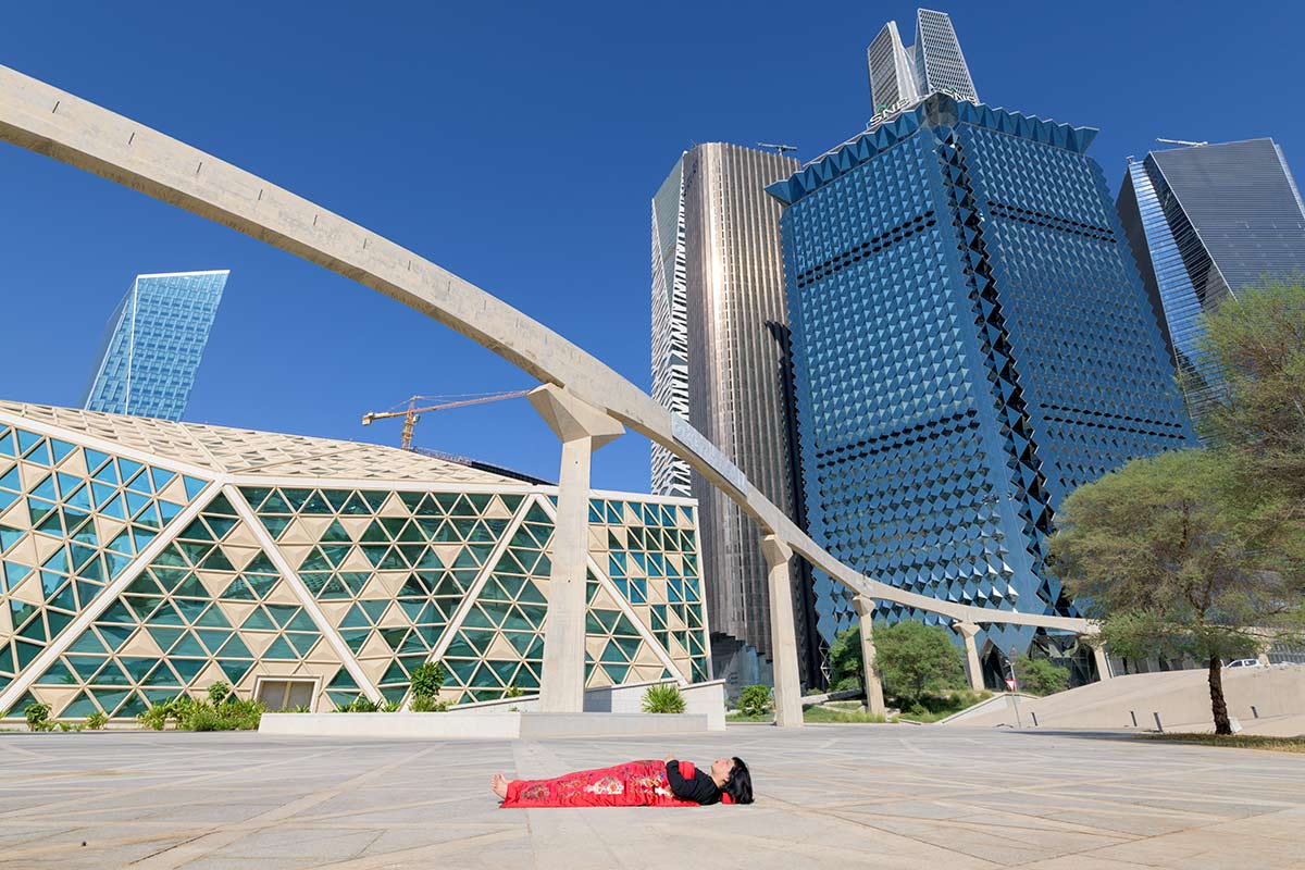 Chun Hua Catherine Dong sleeps in front of the famous architecture in Riyadh, Saudi Arabia, her body is covered with a Chinese red blanket.