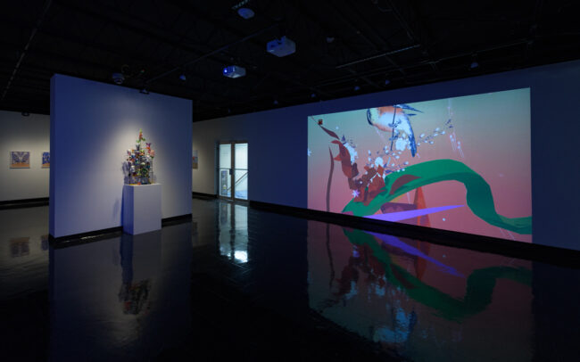 A projection, a sculpture and photographs in a dark gallery space
